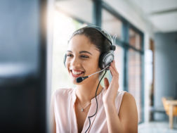 a female tech support agent smiles as she helps a client