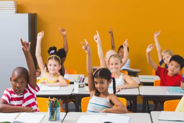 School kids raising hand in classroom